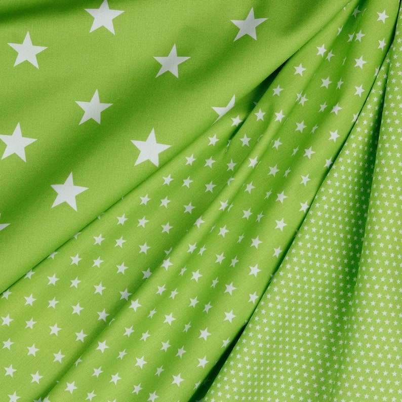 May include: Green fabric with a white star pattern. The fabric has two different patterns, one with larger stars and one with smaller stars.