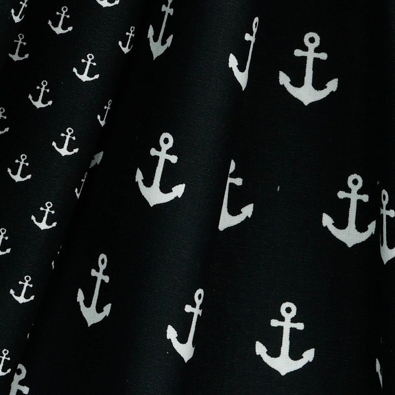 May include: Black fabric with a white anchor pattern. The anchors are repeated throughout the fabric.