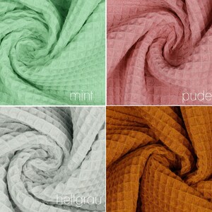 May include: Four fabric swatches in different colors and textures. The swatches are arranged in a grid pattern. The colors are mint green, dusty rose, light gray, and rust orange. The fabric has a waffle texture.
