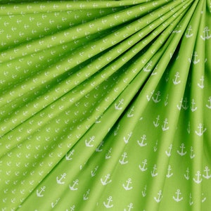 May include: Green fabric with a white anchor pattern. The fabric is folded in a fan shape.