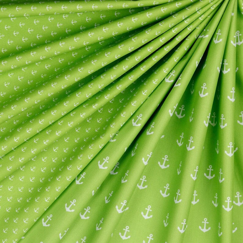 May include: Green fabric with a white anchor pattern. The fabric is folded in a fan shape.