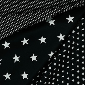 May include: Black fabric with white stars of different sizes. The fabric has a pattern of small white stars on one side and larger white stars on the other side.
