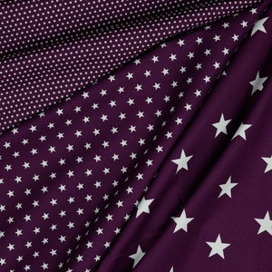 May include: Three pieces of fabric with different patterns of white stars on a deep purple background. The fabric is folded to show all three patterns.