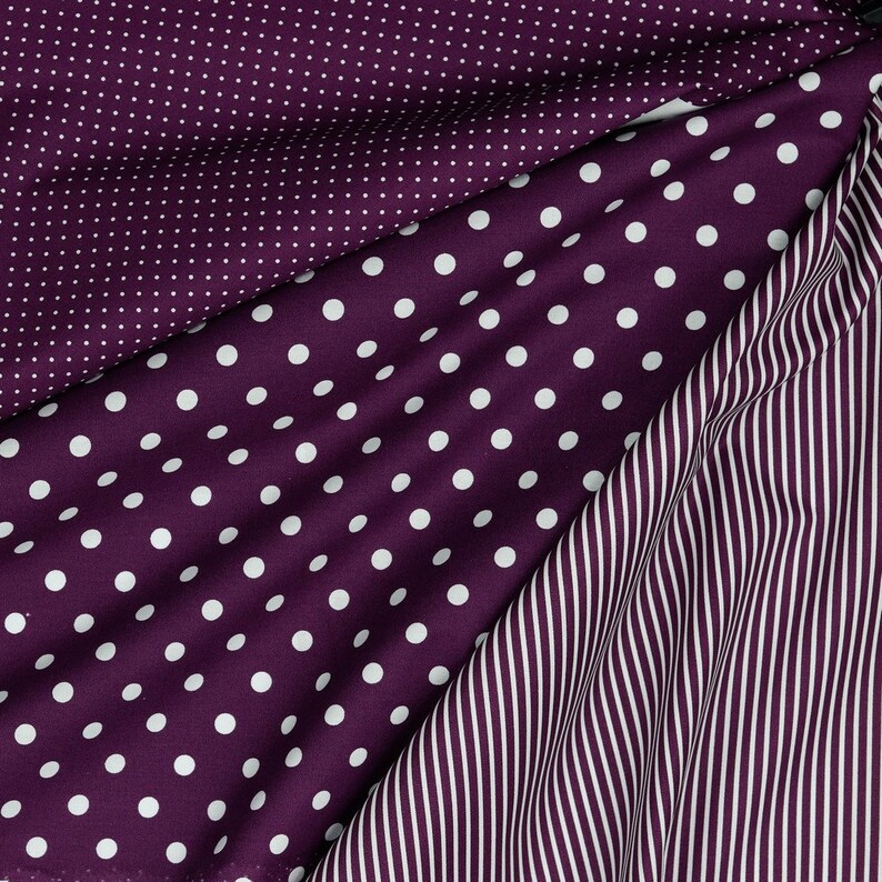May include: Three fabric swatches with different patterns. The top swatch is a purple fabric with small white polka dots. The middle swatch is a purple fabric with large white polka dots. The bottom swatch is a purple and white striped fabric.