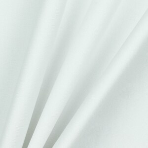 May include: White fabric with a smooth texture and a subtle sheen. The fabric is folded in a way that creates soft, flowing lines.