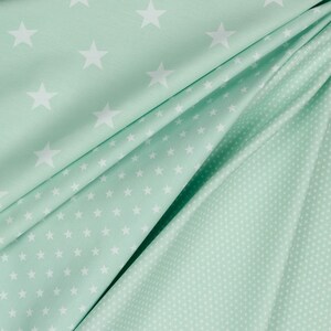 May include: Two pieces of fabric with a mint green background and white stars. One fabric has larger stars and the other has smaller stars.