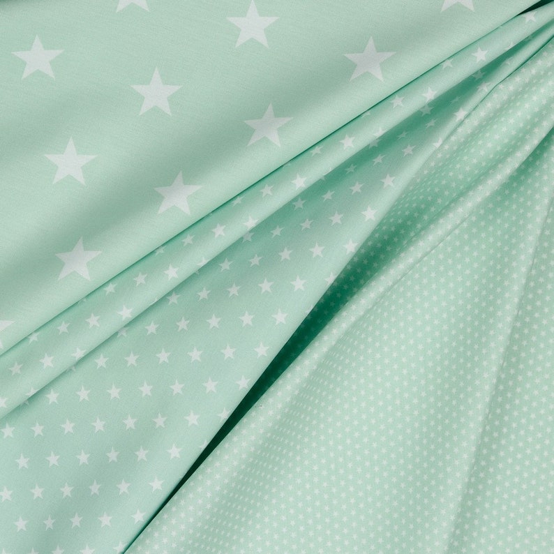 May include: Two pieces of fabric with a mint green background and white stars. One fabric has larger stars and the other has smaller stars.