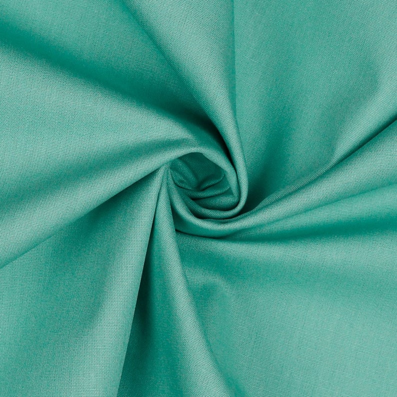 May include: A close-up of a smooth, teal fabric with a soft, wrinkled texture. The fabric is folded and draped, creating a swirling pattern.