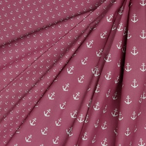 May include: A close-up of a pink fabric with a white anchor pattern. The fabric is folded in half, showing the pattern on both sides.
