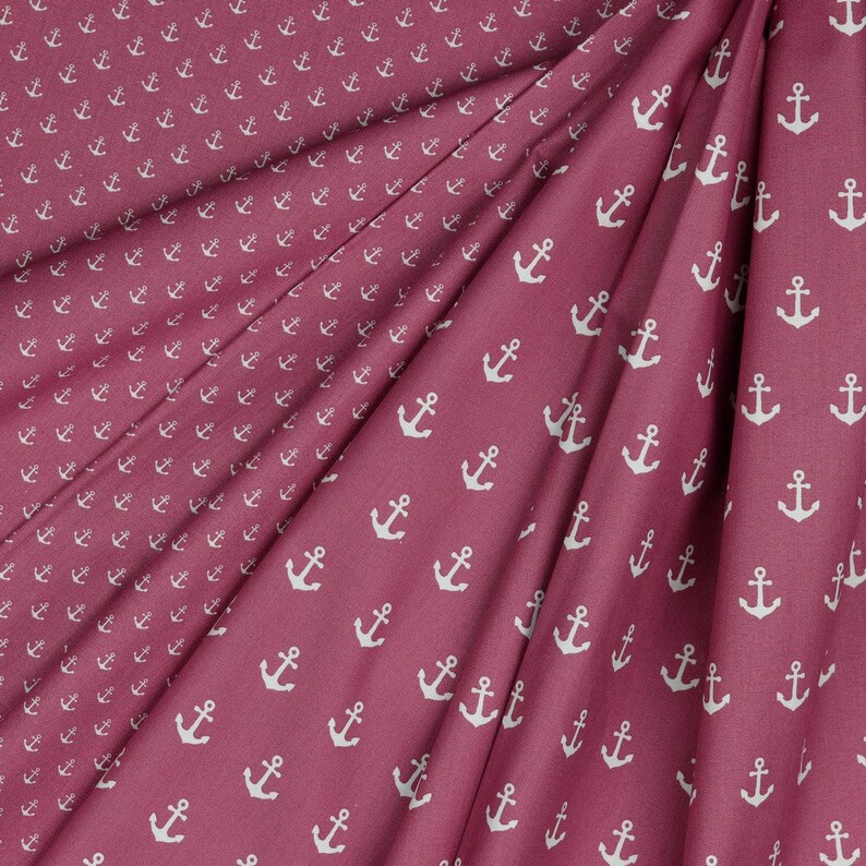 May include: A close-up of a pink fabric with a white anchor pattern. The fabric is folded in half, showing the pattern on both sides.