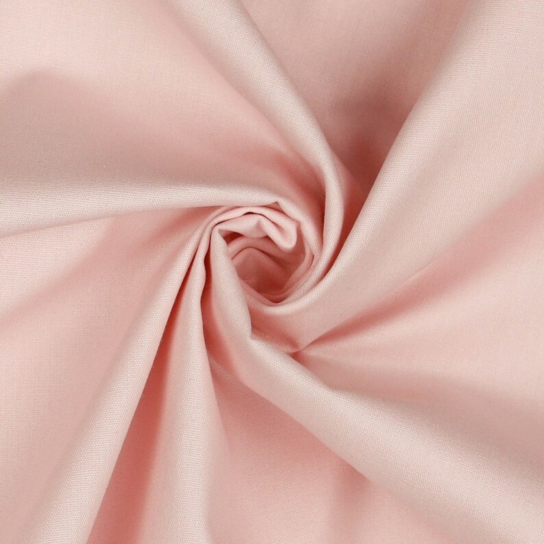 K&ouml;nnte beinhalten: Nahaufnahme eines hellrosa Stoffes mit einem Wirbelmuster. Das Material ist glatt und wirkt leicht, mit sanften Farbtonvariationen. Die Falten und Kurven erzeugen Tiefe und Textur, geeignet f&uuml;r Kleidung oder Heimtextilien.