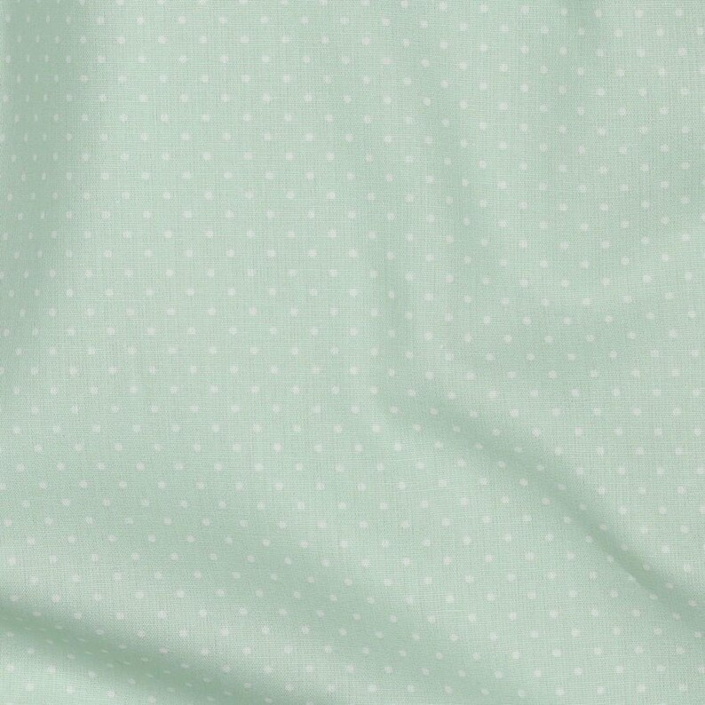 May include: A light green fabric with a white polka dot pattern.