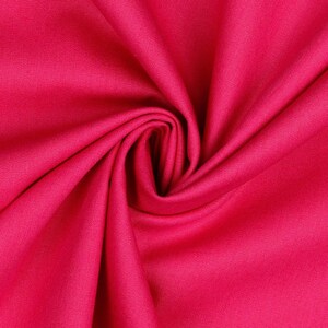 May include: A close-up of a bright pink fabric, folded and draped to show its texture. The fabric is smooth and has a slight sheen.