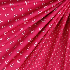 May include: Red fabric with a white anchor pattern. The fabric is folded in half, showing the pattern on both sides.