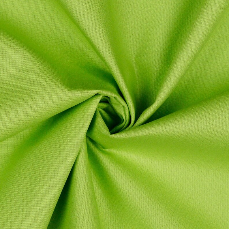 May include: A close-up of a bright green fabric with a smooth texture. The fabric is folded and twisted, creating a soft, flowing look.