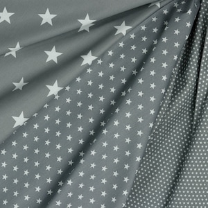 May include: Gray fabric with a white star pattern. The fabric is folded, showing different densities of star arrangements, from large, spaced-out stars to a dense field of small stars. The fabric has a soft, flowing appearance.