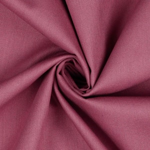 May include: Close-up of a soft, pink fabric with a smooth texture. The fabric is folded and draped, creating a swirling pattern.