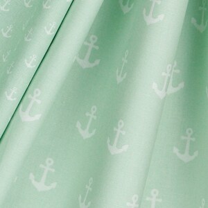 May include: A light green fabric with a white anchor pattern. The fabric is folded and the anchors are visible throughout the pattern.