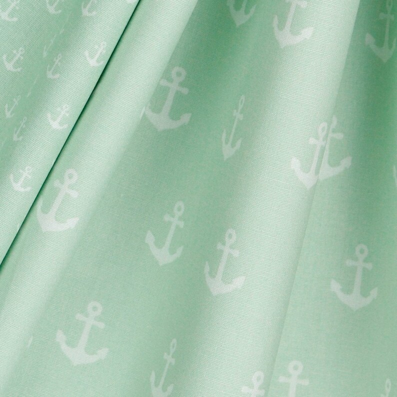 May include: A light green fabric with a white anchor pattern. The fabric is folded and the anchors are visible throughout the pattern.