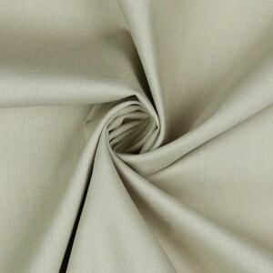 May include: A close-up of a light beige fabric with a smooth texture. The fabric is folded and draped, creating a soft and flowing look.