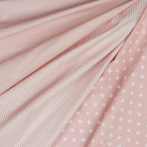 K&ouml;nnte beinhalten: Nahaufnahme von rosa Stoff mit verschiedenen Mustern. Die Muster umfassen kleine wei&szlig;e Tupfen, d&uuml;nne wei&szlig;e Streifen und gr&ouml;&szlig;ere wei&szlig;e Tupfen. Der Stoff ist drapiert und erzeugt Falten und Schatten.