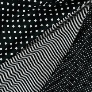 May include: Black and white fabric with three different patterns: polka dots, stripes, and smaller polka dots. The fabric is folded to show all three patterns.