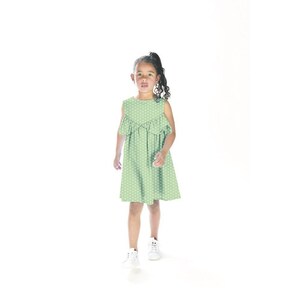 May include: A young girl wearing a green polka dot dress with a ruffled neckline. She is walking towards the camera with a slight smile on her face.