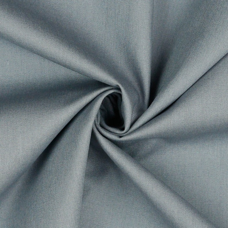 May include: Close-up of a swatch of fabric in a muted teal color. The fabric is tightly woven, with visible texture and folds, creating shadows and highlights. The fabric is gathered in a spiral, with a dark center.