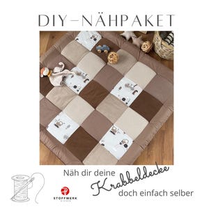 Könnte beinhalten: Eine quadratische Patchwork-Krabbeldecke mit einem Karomuster aus einfarbig braunen, strukturiert beigen und weißen Stoffquadraten mit Traktormotiv. Der Text DIY-NÄHPAKET und Näh dir deine Krabbeldecke doch einfach selber ist zu sehen.