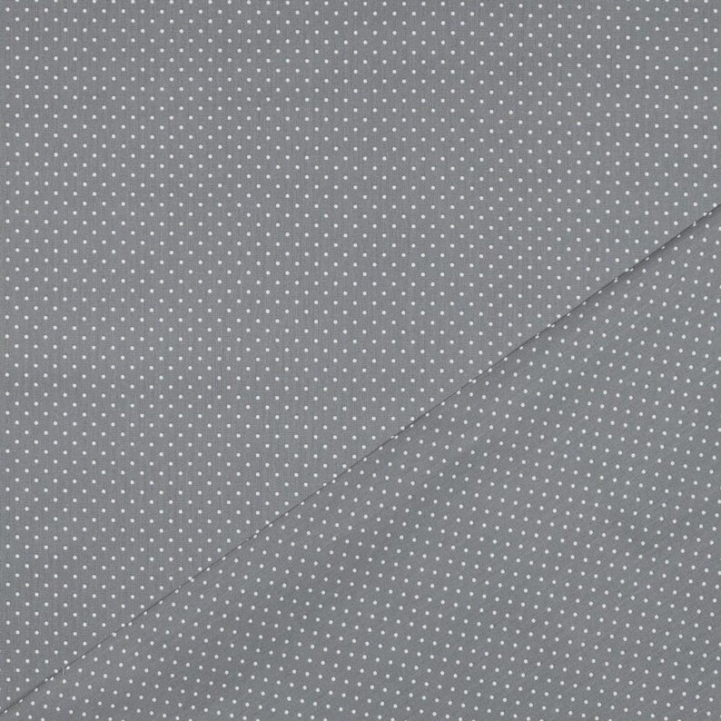Pu&ograve; includere: Un tessuto grigio con un motivo a pois bianchi. Il tessuto &egrave; piegato a met&agrave;, creando una linea diagonale.