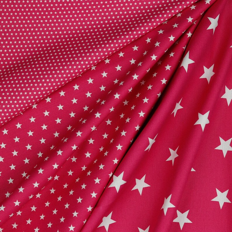 May include: Two red fabric swatches with white stars. One swatch has small white stars on a red background, and the other has larger white stars on a red background.