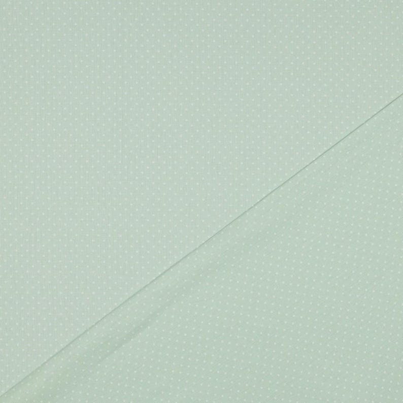 May include: A light green fabric with a white polka dot pattern.