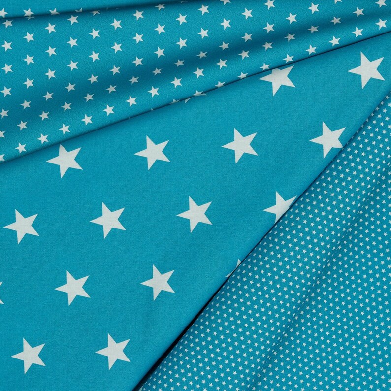 May include: Two pieces of fabric with a blue background and white stars. One fabric has large stars and the other has small stars.