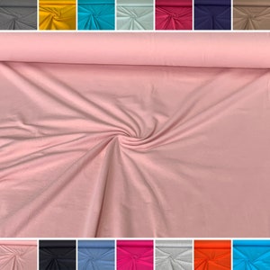 May include: A close-up of a pink fabric swatch. The fabric is soft and smooth, and it has a slight sheen. The fabric is rolled up and the edges are visible. The fabric is available in a variety of colors.