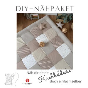 May include: A square patchwork play mat featuring a grid of beige, white, and brown fabric squares with polka dot and star patterns. The text DIY-NÄHPAKET and Näh dir deine Krabbeldecke doch einfach selber appears alongside a spool and needle icon.