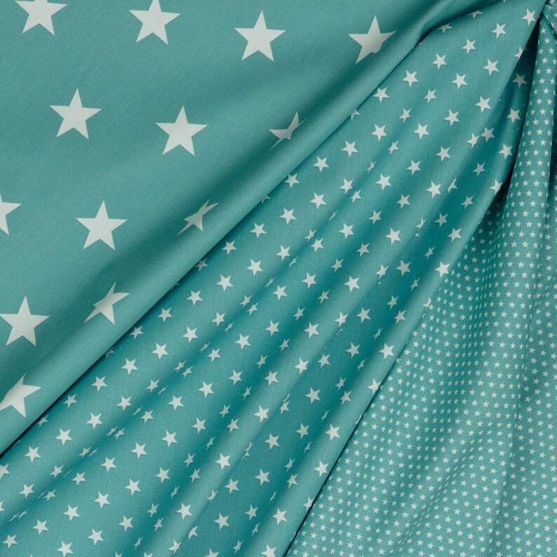 May include: Two pieces of teal fabric with white star patterns. One fabric has large stars and the other has small stars.