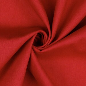 Pode incluir: Um close-up de um tecido vermelho com uma textura lisa. O tecido é dobrado e drapeado, criando um visual suave e fluido.