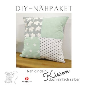 May include: DIY sewing kit for a pillow with a patchwork design featuring elephants, stars, and polka dots in shades of green and gray. The text "Näh dir dein Kissen doch einfach selber" is included in the image.