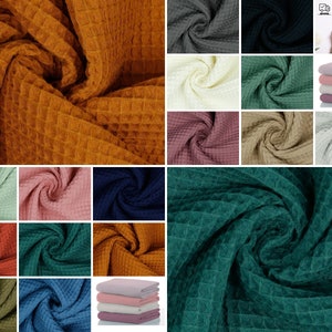 May include: A collection of waffle weave fabric swatches in various colors, including mustard yellow, sage green, navy blue, teal, and pink. The fabric is soft and textured, with a waffle-like pattern.