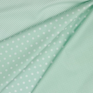 May include: Three pieces of fabric in different patterns. The top piece is a light green fabric with white stripes. The middle piece is a light green fabric with white polka dots. The bottom piece is a light green fabric with a small white dot pattern.