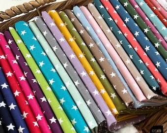 Può includere: Una collezione di 24 campioni di tessuto con un motivo a stelle bianche su diversi sfondi colorati. I tessuti sono disposti in un cesto e sono etichettati con "Stoffwerk Siegen".