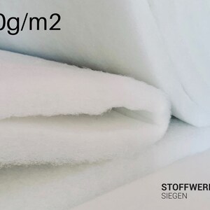 Pode incluir: Algodão de tecido branco, dobrado em camadas, com o texto "400g/m2" impresso na camada superior. O tecido é um material branco macio, e o texto está em preto.