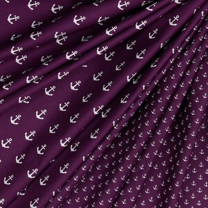 May include: Purple fabric with a white anchor pattern. The anchors are repeated in a smaller size on the bottom right corner of the fabric.