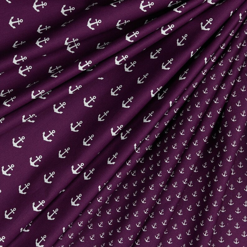 May include: Purple fabric with a white anchor pattern. The anchors are repeated in a smaller size on the bottom right corner of the fabric.