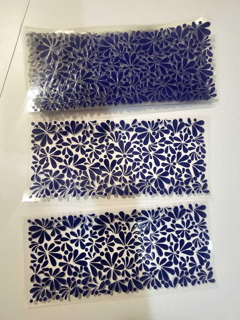 May include: Three clear plastic sheets with a repeating pattern of navy blue floral designs. The floral pattern is composed of stylized flowers and teardrop shapes. The sheets are stacked on a white surface.
