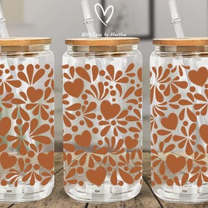 May include: Clear glass drinking jars with brown heart and floral patterns, bamboo lids, and clear straws. The jars are displayed on a wooden surface. The text "With Love, by Martha" is visible on the top.