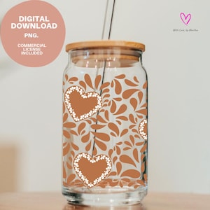 Puede incluir: Un vaso de vidrio transparente con tapa de bambú y pajita de vidrio. La taza está decorada con corazones marrones delineados con flores blancas y formas de hojas marrones. El texto "DESCARGA DIGITAL PNG. LICENCIA COMERCIAL INCLUIDA" está en un círculo rosa.