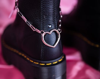May include: Black leather boots with a chunky platform sole and a silver chain with a heart charm around the ankle.
