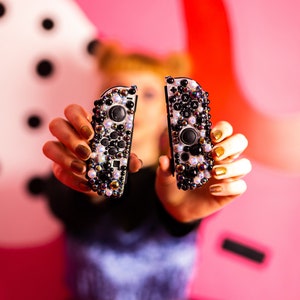 May include: Two black and white Nintendo Switch Joy-Con controllers with a sparkly, iridescent design.