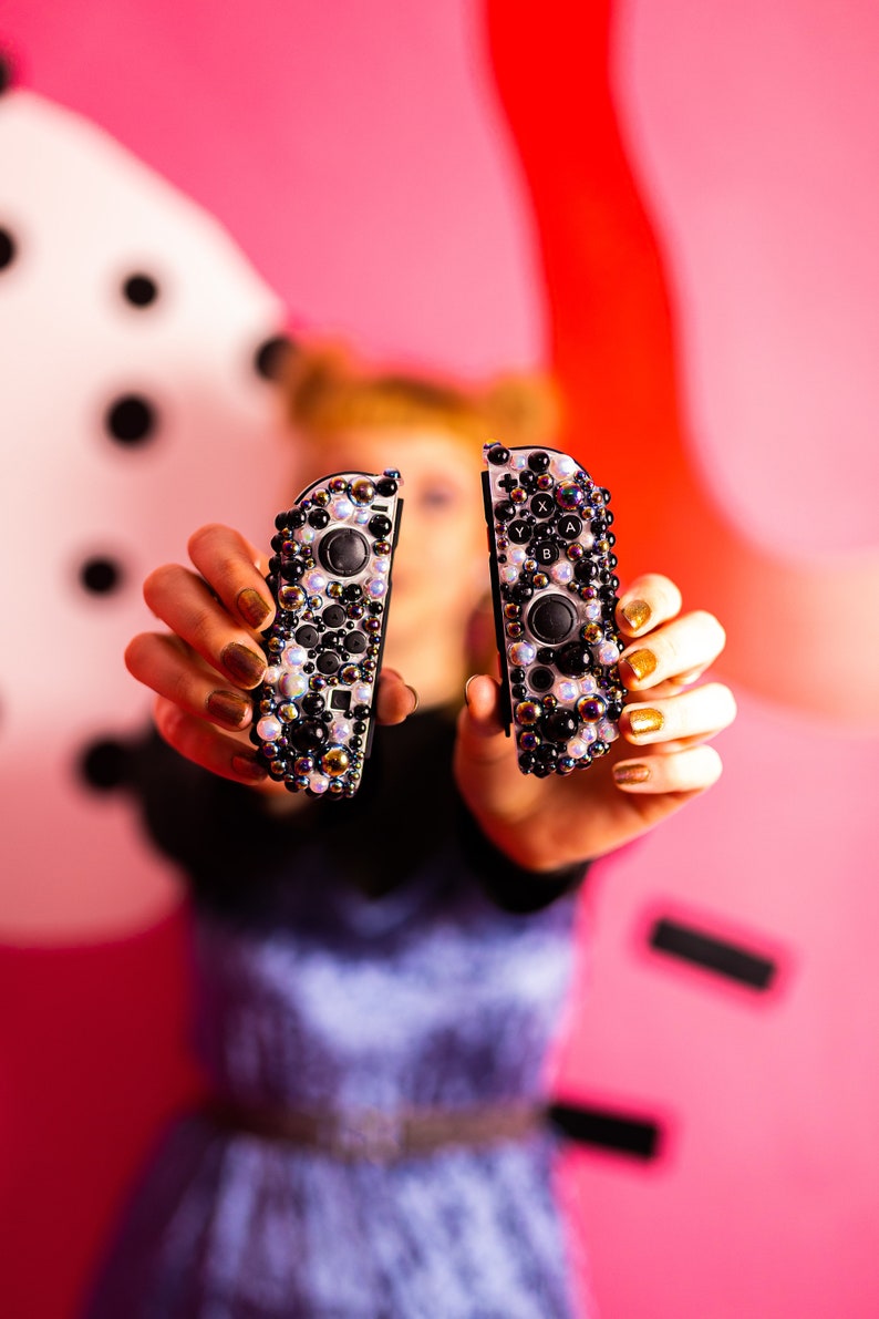 May include: Two black and white Nintendo Switch Joy-Con controllers with a sparkly, iridescent design.